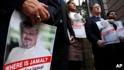 Alyssa Edling, center, and Thomas Malia, second from right, both with PEN America, join others as they hold signs of missing journalist Jamal Khashoggi, during a news conference about his disappearance in Saudi Arabia, Oct. 10, 2018, in front of The Washington Post in Washington. 