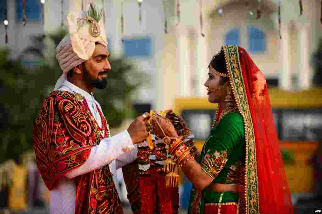 اجتماعی شادی کی تقریب میں ایک جوڑا ہندو مذہب کے مطابق ایک دوسرے کے گلے میں پھولوں کا ہار ڈال رہا ہے۔ &nbsp;