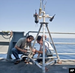 Study author Timothy Crone (left) prepares to deploy a camera designed to monitor the flow of hydrothermal vents off the US Pacific Northwest