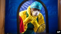 FILE - a healthcare worker dons protective gear before entering an Ebola treatment center in the west of Freetown, Sierra Leone. 