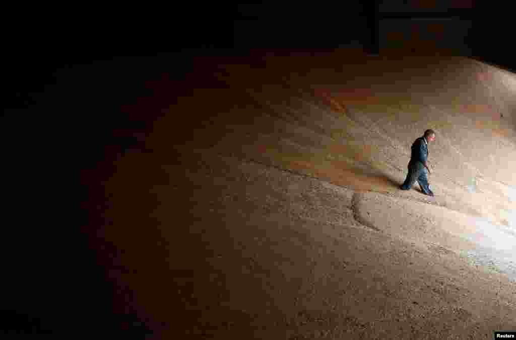 French farmer Olivier Chatellier walks on harvested grains of wheat stored in Vieillevigne near Nantes, France.