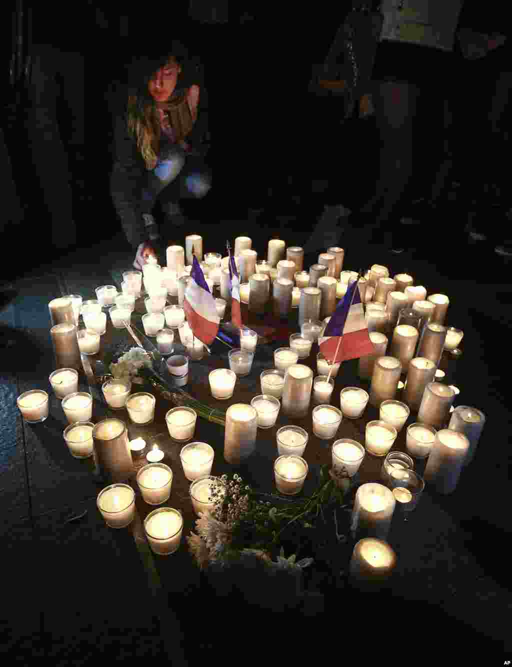 A young woman places candles a circle during a vigil in a tribute to the victims of the Bastille Day attack, in Sydney, Australia on July 15, 2016.