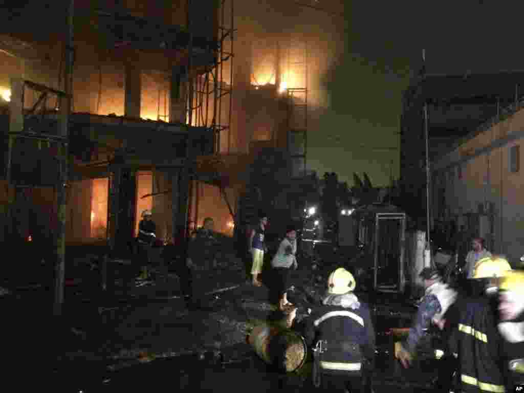 Iraqi firefighters and civilians gather at the site after a car bomb at a commercial area in Karada neighborhood, Baghdad, July 3, 2016.