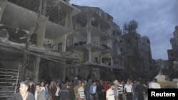 A crowd gathers in front of damaged buildings after a car bomb exploded at Daf al-Shok district, in Damascus, Syria, October 26, 2012, in this photograph released by Syria's national news agency SANA.
