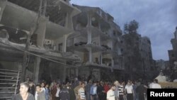 Warga mengamati bangunan yang hancur pasca ledakan bom mobil di Daf al-Shok, Damaskus, Suriah (26/10). 
