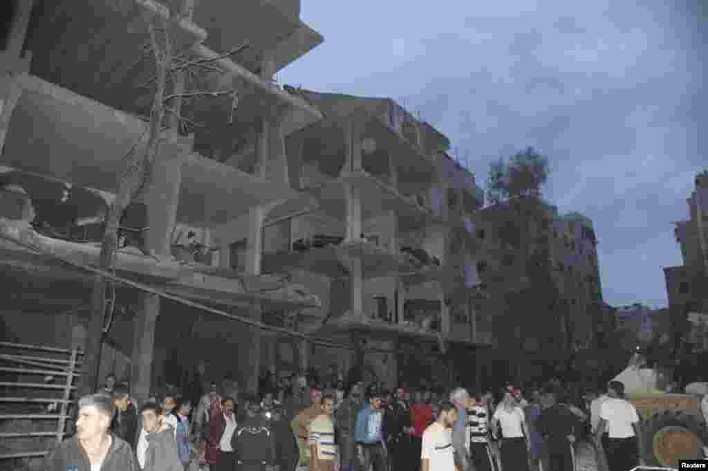 A crowd gathers in front of damaged buildings after a car bomb exploded at Daf al-Shok district, in Damascus, Syria, October 26, 2012, in this photograph released by Syria's national news agency SANA.