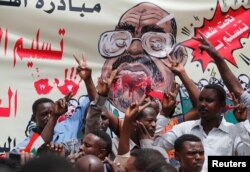 Protesters shout slogans by a banner depicting former Sudanese President Omar al-Bashir, in front of the Defense Ministry in Khartoum, Sudan, April 19, 2019.