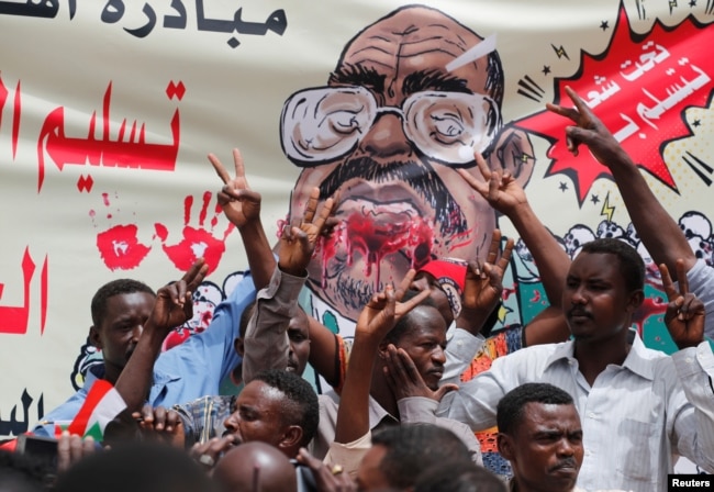 Protesters shout slogans by a banner depicting former Sudanese President Omar al-Bashir, in front of the Defense Ministry in Khartoum, Sudan, April 19, 2019.