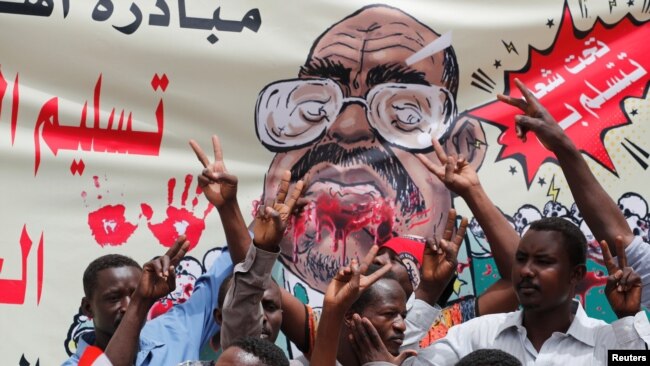 Protesters shout slogans by a banner depicting former Sudanese President Omar al-Bashir, in front of the Defense Ministry in Khartoum, Sudan, April 19, 2019. 