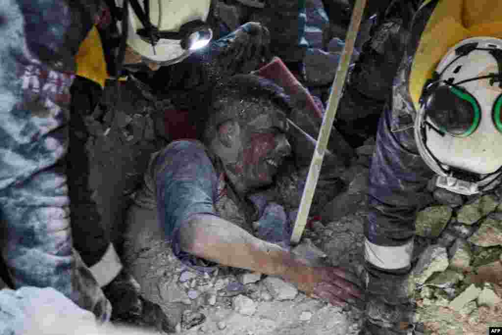 Members of the Syrian Civil Defense, also known as the White Helmets, rescue a survivor from the rubble of a collapsed building following a reported airstrike in the village of Balyun in Syria&#39;s northwestern Idlib province, Dec. 7, 2019.