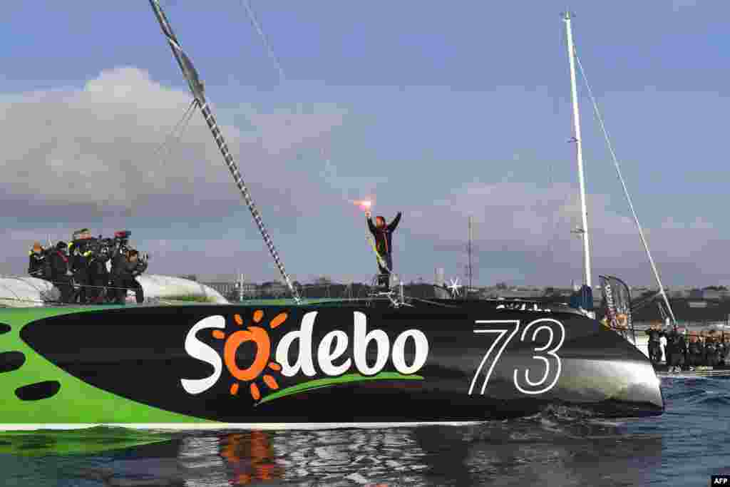 French skipper Thomas Coville (C) holds a burning flare onboard his &quot;Sodebo Ultim&#39;&quot; multihull as he arrives in the port of Brest, western France, after beating the record in solo non-stop round the world sailing.&nbsp;Coville, 48, slashed eight days off the record when he ended an astonishing solo non-stop circumnavigation of the World on his 31m maxi trimaran on Dec. 25, 2016, in just 49 days, 3 hours, 7mins and 38secs.
