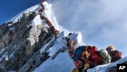 En esta fotografía del 22 de mayo de 2019, una larga fila de montañistas ascienden al pico del Everest. (Nimsdai Project Possible vía AP)