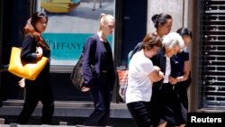 在澳大利亞城市悉尼，一名槍手在市中心商業區一家餐館扣押了人數不詳的人質﹐圖為咖啡廳旁建築物一名婦女在警方幫忙下疏散。