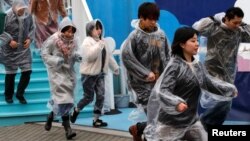 FILE - Participants run during an anti-missile evacuation drill at the Tokyo Dome City amusement park in Tokyo, Jan. 22, 2018. 