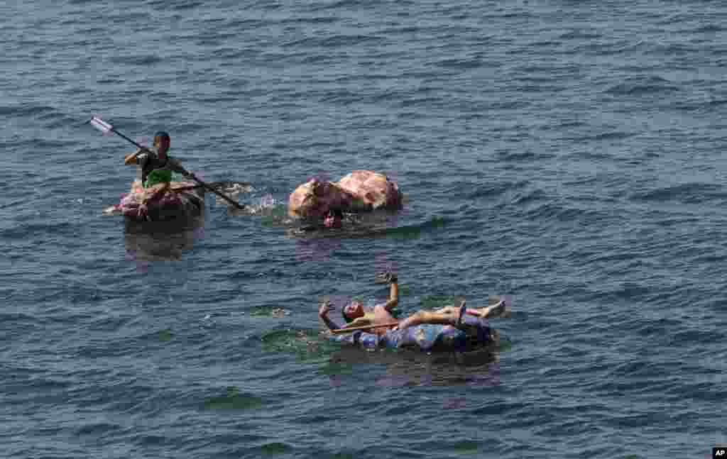 Boys paddle their handmade rafts in the Mediterranean Sea off the coast of the Shati Refugee Camp, in Gaza City, March 19, 2018.