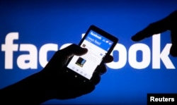 FILE - A smartphone user displays a Facebook newsfeed, May 2, 2013.