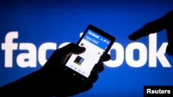 FILE - A smartphone user displays a Facebook newsfeed in a May 2, 2013, photo illustration. 