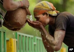بھارت میں گرمی کی شدت سے پریشان ایک مزدور پانی پی رہا ہے۔ فائل فوٹو