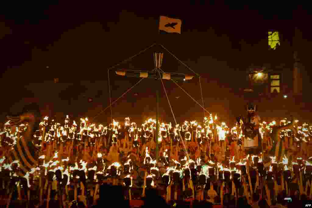 Guizers dressed as Vikings from the Jarl Squad surround the long ship with burning brands as the Guizer Jarl (C) stands aboard as they take part in the Up Helly Aa festival in Lerwick, Shetland Islands, United Kingdom, Jan. 29, 2019.