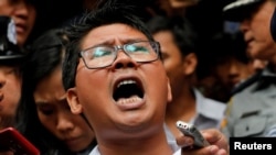 លោក Wa Lone (កណ្តាល) ដែល​ជា​អ្នក​កាសែត​របស់​បណ្តាញ​សារព័ត៌មាន Reuters និយាយ​ទៅ​កាន់​អ្នក​កាសែត​នានា ខណៈ​ដែល​លោក​ត្រូវ​បាន​ប៉ូលិស​នាំ​ខ្លួន​ចេញ​ពី​តុលាការ​ក្នុង​ទីក្រុង Yangon ប្រទេស មីយ៉ាន់ម៉ា កាល​ពី​ថ្ងៃ​ទី ៣ ខែ កញ្ញា ឆ្នាំ ២០១៨។ តុលាការ​ក្នុង​ប្រទេស មីយ៉ាន់ម៉ា បាន​កាត់ទោស​អ្នកកាសែត Reuters ពីរ​នាក់ ឲ្យ​ជាប់​ពន្ធនាគារ​រយៈពេល​៧​ឆ្នាំ ចំពោះ​ការ​រក្សា​ទុក​ឯកសារ​ផ្លូវការ​ដោយ​ខុសច្បាប់ ដែល​សាលក្រម​នេះ​ត្រូវ​បាន​ធ្វើ​ឡើង ខណៈ​ដែល​សហគមន៍​អន្តរជាតិ​រិះគន់​ទៅ​លើ​ការ​ចោទប្រកាន់​ថា រដ្ឋាភិបាល​មីយ៉ាន់ម៉ាបំពាន​សិទ្ធិ​ជនជាតិ​រ៉ូហ៊ីងយ៉ា ដែល​កាន់​សាសនា​ឥស្លាម។ (AP Photo/Thein Zaw)