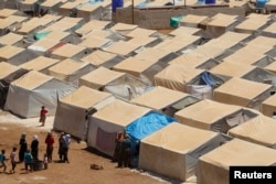 Women talk and children play around the tents of the Bab Al-Nour internally displaced persons (IDP) camp, north of Aleppo, beside the Syrian-Turkish border, May 18, 2014.