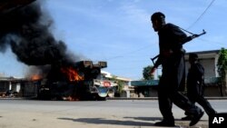 Pakistani paramilitary troops inspect burning NATO trucks in the Pakistani tribal area of Jamrud near Peshawar, Pakistan, May, 5, 2014.