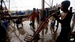 FILE - Migrant workers unload frozen fish from a boat at a fish market in Samut Sakhon Province, west of Bangkok, Thailand, June 20, 2014. 