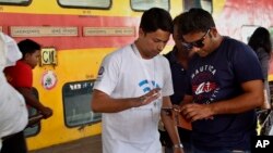 A volunteer from Google Inc. helps Indian travellers log on to a free WiFi service at Mumbai Central Train Station in Mumbai, India, Jan. 22, 2016.