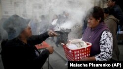 In this picture taken Monday, Jan. 6, 2020, spiritual indigenous guide Josefa Oblitas blesses a woman's baby Jesus doll outside the San Francisco Church during the Three Kings Day celebrations in La Paz, Bolivia.
