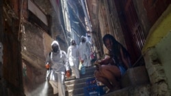 Volunteers spray disinfectant in an alley to help contain the spread of the new coronavirus at the Santa Marta slum in Rio de Janeiro, Brazil, Saturday, Nov. 28, 2020.