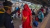 A health worker checks the temperature of a traveler as a precaution against the coronavirus before allowing her to proceed at a train station in Mumbai, India, Nov. 30, 2021.