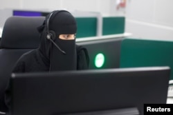 FILE - A Saudi woman works inside the first all-female call center in the kingdom's security sector, in the holy city of Mecca, Saudi Arabia, Aug. 29, 2017