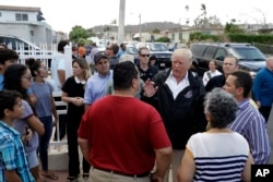 President Donald Trump and Puerto Rico Governor Ricardo Rosselló, center, listen to residents and survey hurricane damage and recovery efforts in a neighborhood in Guaynabo, Puerto Rico, Tuesday, Oct. 3, 2017.