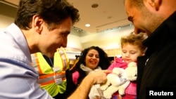 PM Kanada Justin Trudeau (kiri) menyambut langsung kedatangan rombongan pertama pengungsi Suriah di kota Toronto, Kamis malam (10/12). Kanada telah menyatakan kesediaan menampung 25.000 pengungsi Suriah sebelum akhir Februari 2016. 