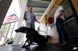 FILE - Virginia voter Harry Donahue talking to his wife Nancy on the front porch of their farmhouse, built in the 1700's, in Farmville, Va. (AP Photo/Steve Helber)