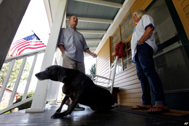 FILE - Virginia voter Harry Donahue talking to his wife Nancy on the front porch of their farmhouse, built in the 1700's, in Farmville, Va. (AP Photo/Steve Helber)