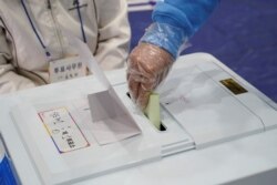 Seorang pemilih mengenakan sarung tangan plastik memasukkan surat suara di tempat pemungutan suara dalam pemilu legislatif di tengah pandemi virus corona di Seoul, Korea Selatan, 15 April 2020. (Foto: Reuters)