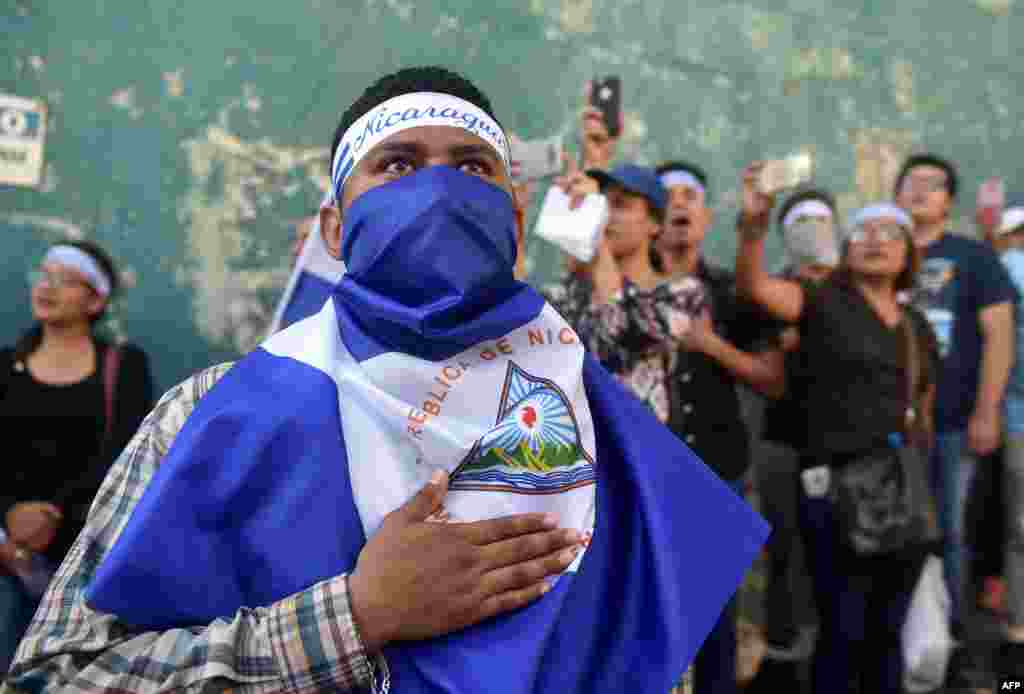 Demonstrators sing the national anthem in front of the Police Station during a protest against the government of President Daniel Ortega, in Managua, Nicaragua.