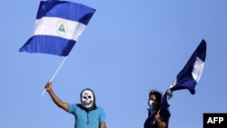 Un hombre y una mujer ondean banderas nacionales nicaragüenses durante una protesta contra el gobierno del presidente nicaragüense, Daniel Ortega, en Managua.