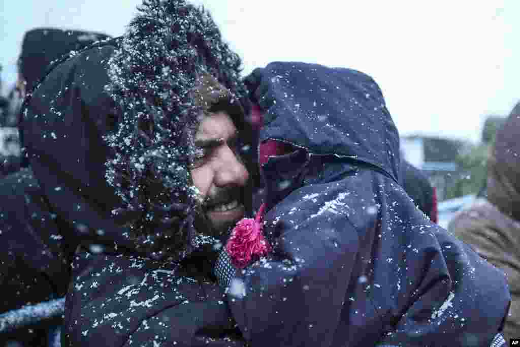 A migrant holds his child as he waits to get meal during a snowfall outside a logistics center at the checkpoint &quot;Kuznitsa&quot; at the Belarus-Poland border near Grodno, Belarus.