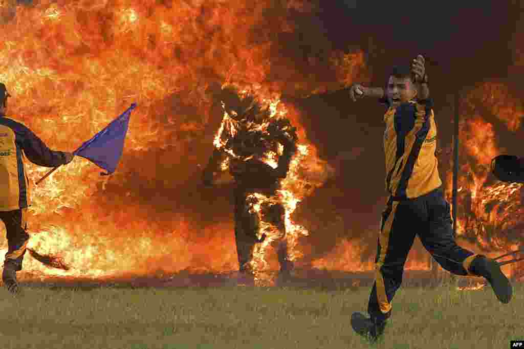 Daredevil motorcycle rider Captain Shivam Singh (C) from the 'Tornadoes' motorcycle acrobatic team of the Indian Armed Forces comes out ablaze after catching fire while riding his bike through a tunnel of fire during an attempt to break the Guinness Book in Bangalore.