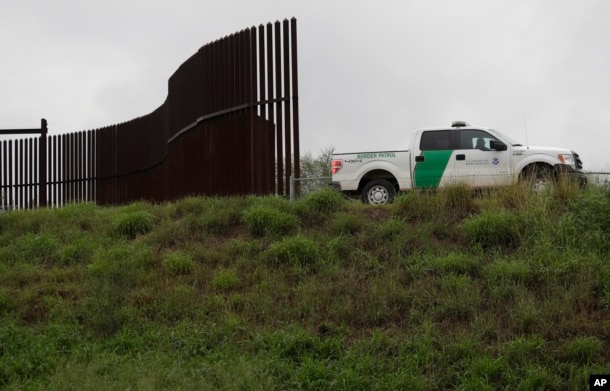 FILE - U.S. Customs and Border Patrol agent passes along a section of border wall in Hidalgo, Texas.