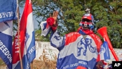 FILE - A supporter of the New Patriotic Party (NPP) wears campaign paraphernalia on the side of a road in Accra, Ghana, Nov. 23, 2012. The NPP has said it will challenge the ruling National Democratic Congress party with its own manifesto October 18.