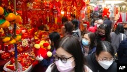People walk past Chinese New Year decorations at a market to celebrate the Lunar New Year in Hong Kong, Monday, Jan. 31, 2022. The Chinese Lunar New Year falls on Feb. 1. (AP Photo/Vincent Yu)