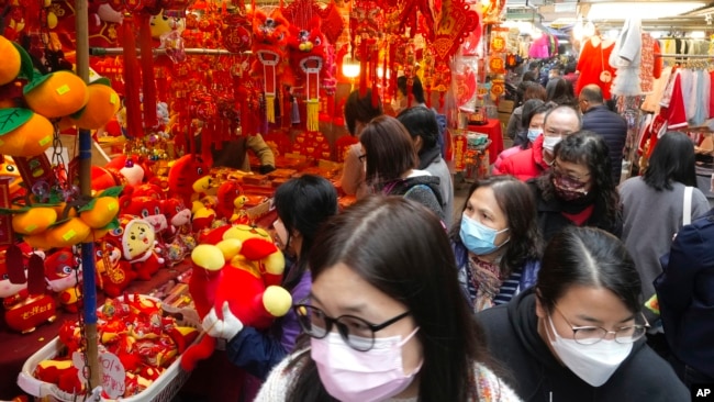People walk past Chinese New Year decorations at a market to celebrate the Lunar New Year in Hong Kong, Monday, Jan. 31, 2022. The Chinese Lunar New Year falls on Feb. 1. (AP Photo/Vincent Yu)