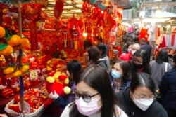 Orang-orang berjalan melewati dekorasi Tahun Baru Imlek di pasar untuk merayakan Tahun Baru Imlek di Hong Kong, Senin, 31 Januari 2022. Tahun Baru Imlek jatuh pada 1 Februari (Foto: AP/Vincent Yu)