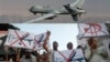 FILE - This composite image shows a U.S. Air Force drone that was piloted during missions over the tribal regions of Pakistan and Afghanistan, and Pakistan's Islamist party Pasban (bottom photo) protesting against U.S. drone attacks in the Pakistani tribal region, Karachi, Pakistan.