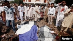 Cư dân bên cạnh các thi thể tại hiện trường vụ đánh bom tự sát tại Nhà Thờ All Saints ở thành phố Peshawar, phía Bắc Pakistan, ngày 22/9/2013.