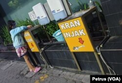 Seorang anak memakai masker dan faceshield sedang mencuci tangan di wastafel, di pusat penjualan elektronik di Surabaya (foto Petrus Riski-VOA).