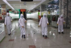 FILE - Staff of the Pyongyang Department Store No. 1 disinfect the store to help curb the spread of the coronavirus before it opens in Pyongyang, North Korea, Dec. 28, 2020.